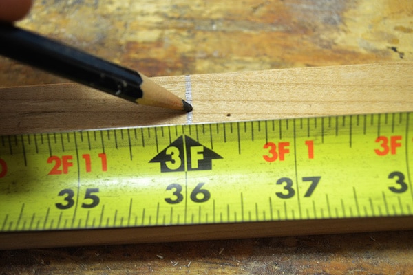 Man using pencil to take measurement with inches footer. 