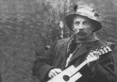 Learn how to make a cigar box guitar with this old black and white photo of a man playing an acoustic guitar.