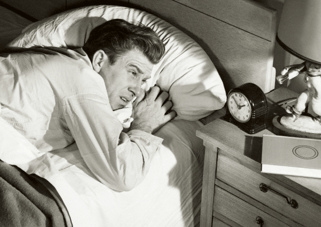 Vintage man in bed looking at the clock. 
