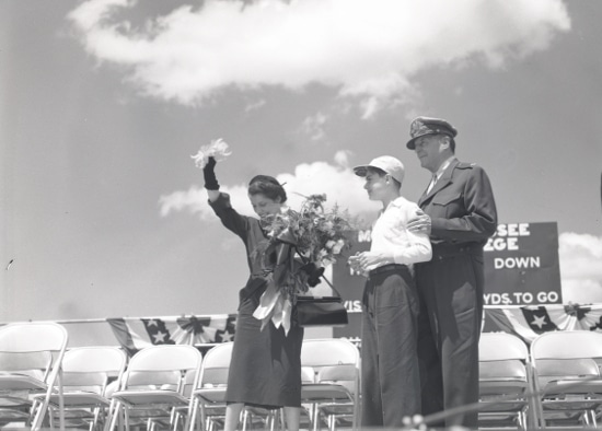Douglas MacArthur standing with his wife and son in stadium. 