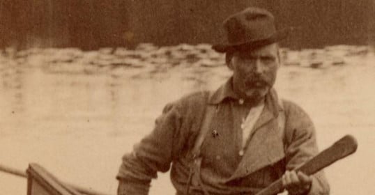 A man in a canoe, paddling with a J-stroke.