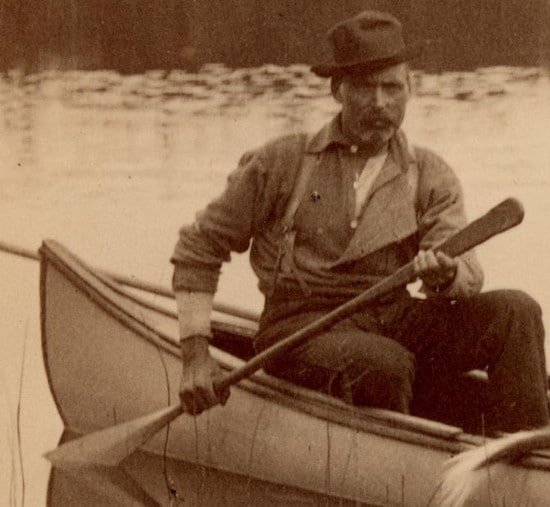 Vintage man with stern look in canoe, paddling water.