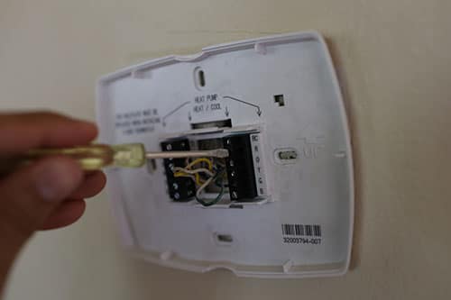 Technician disconnecting the wires from old thermostat. 