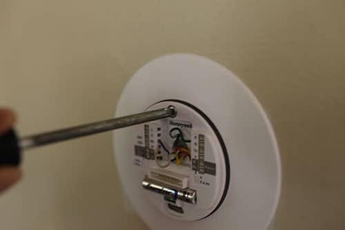 Man tighten the screw of thermostat with screw driver.