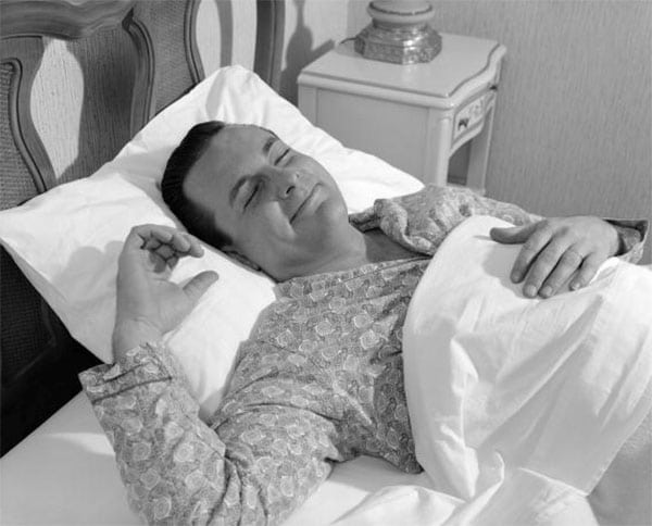 Vintage man in bed sleeping with smiling face. 