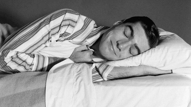 Man sleeping peacefully on his bed wearing pajamas.