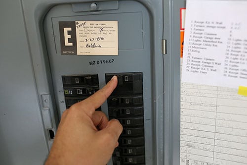 Man turning off electrical switch in power panel. 