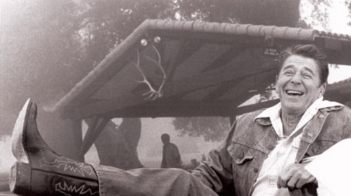 A man in a cowboy hat sitting at a table, embodying the Western Boots aesthetic.