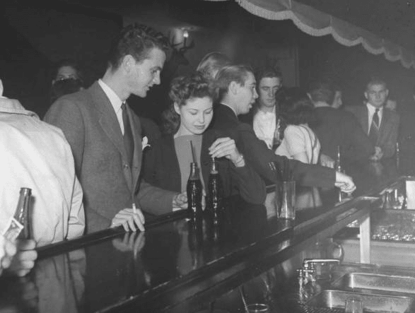 A group of shy guys standing at a bar, overcoming shyness.