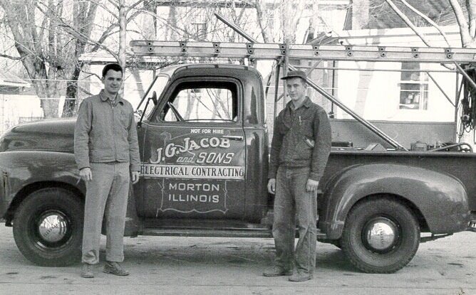 vintage electricians standing in front of company truck