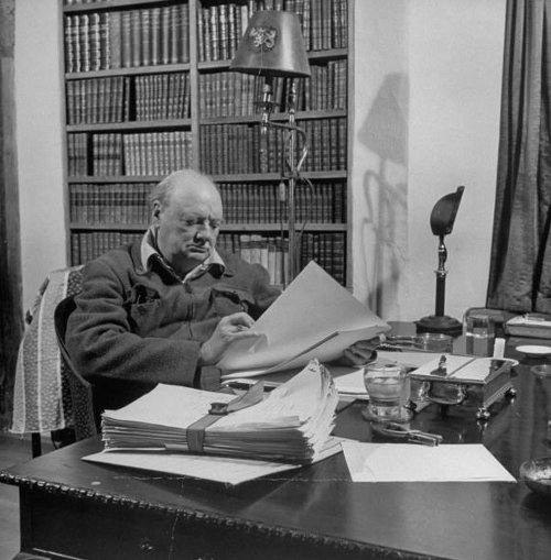 Winston Churchill sitting at Desk in Library reading.