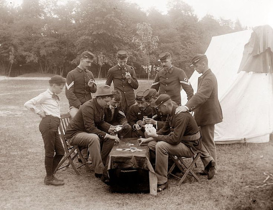 Soldiers in uniform playing cards in camp. 