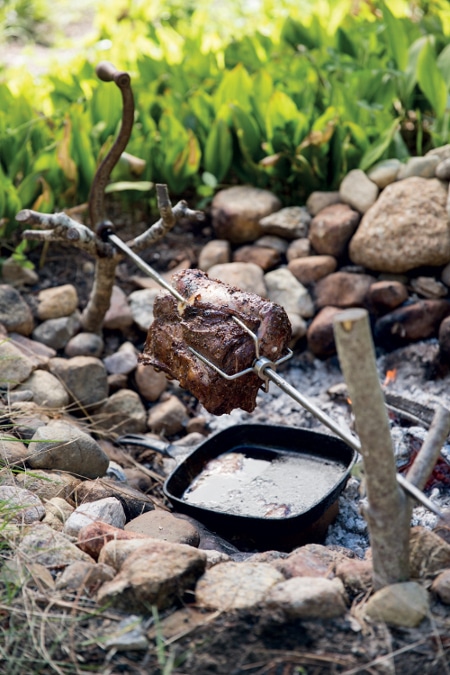 metal cooking spit with meat forks pork roast