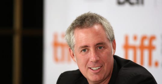 A man smiling at a microphone during a podcast recording.
