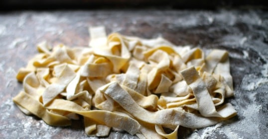 Fresh pasta fettuccine noodles on a baking sheet.