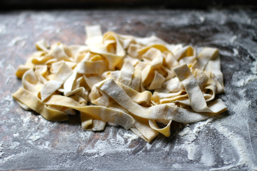 Fresh pasta fettuccine noodles on a baking sheet.