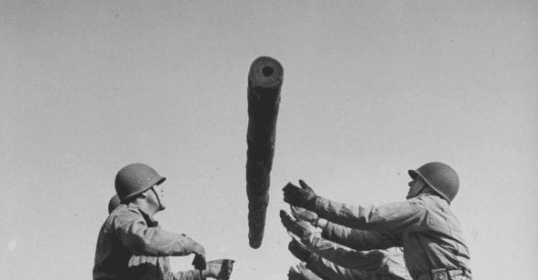 A group of soldiers are holding a large object during WWII.