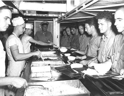 Vintage soldiers in mess dining hall being served food. 