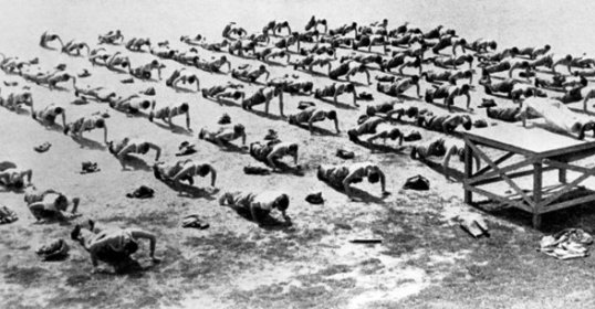 During WWII Workout Week, a large group of people is seen standing in a field.