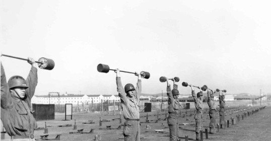 A group of men in a Strength Course doing squats with barbells during WWII Workout Week.