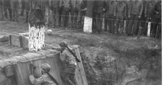 A group of soldiers, demonstrating the importance of physical fitness, are climbing over a wall during WWII Workout Week.