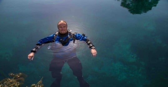 An underwater archaeologist exploring a clear body of water.