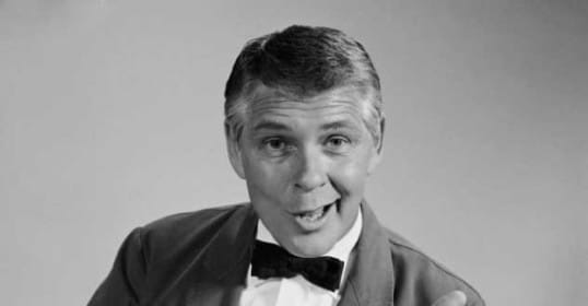A black and white photo of a man in a stylish tuxedo.