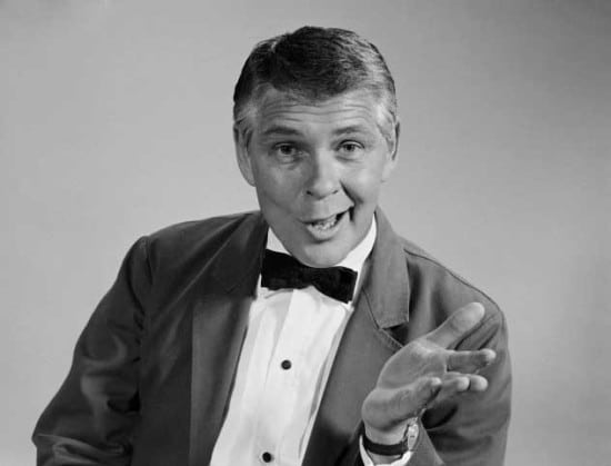 A black and white photo of a man in a stylish tuxedo.