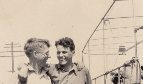 Two men standing next to a boat, possibly making friends during their adulthood.
