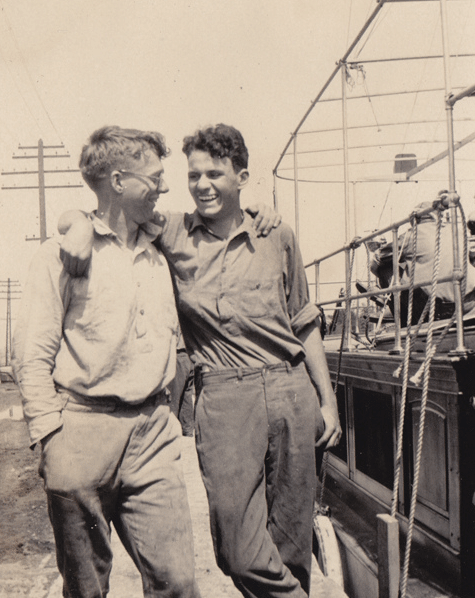 Two men standing next to a boat, possibly making friends during their adulthood.