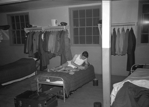 Vintage soldier reading a book on bed. 