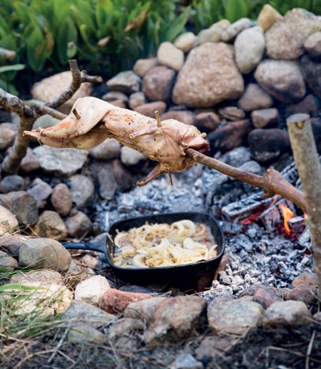 A campfire with a pan full of food, perfect for primal cooking.