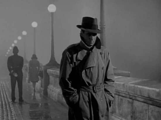 Vintage Man walking across Bridge in trench Coat. 