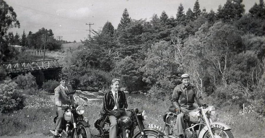 Three men on motorcycles enjoying their hobby on a dirt road.