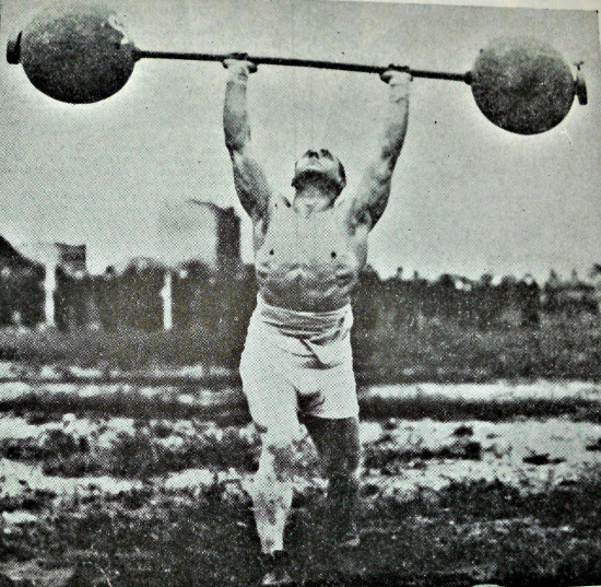 Vintage man strongman lifting heavy barbell overhead press.