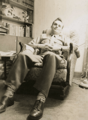 Vintage man sitting in chair arms folding on lap. 