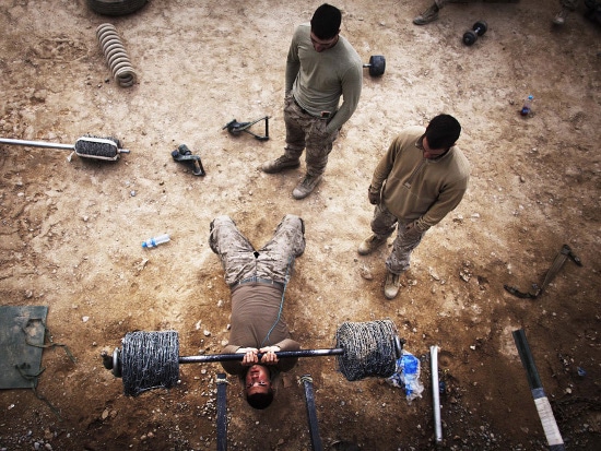 Soldier weight lifting with barbell overhead. 