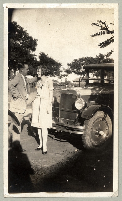 A couple is standing infront of car.