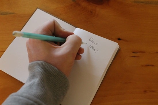 A man writing on page with pencil.