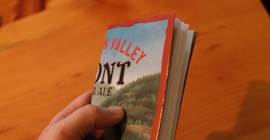 A person holding a book with a bear on a carton.