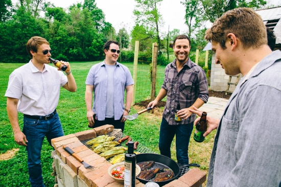 Man in yard grilling with friends. 