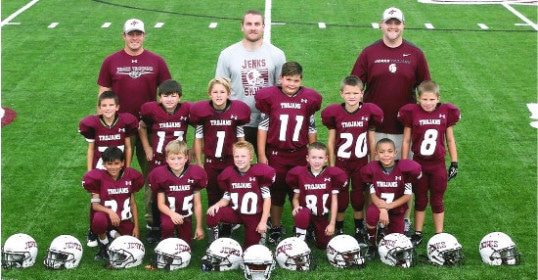 A team of boys in maroon football uniforms posing for a photo during youth sports.