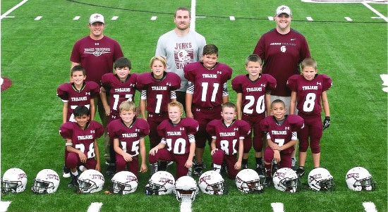 A team of boys in maroon football uniforms posing for a photo during youth sports.