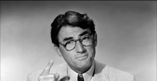 A black and white photo of a man wearing a seersucker suit and glasses.