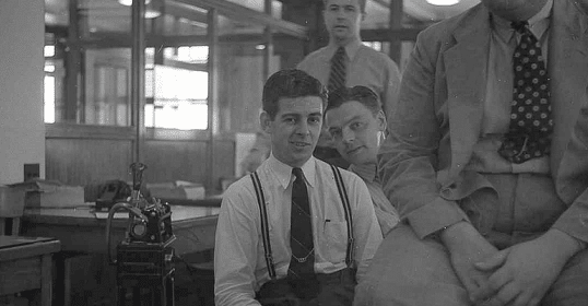A group of men sitting in a room discussing a deal.