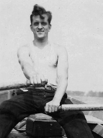 An old photo of a man joyfully in a boat.