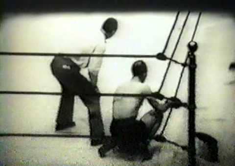 Vintage boxer sitting in corner of ring with trainer. 