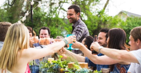 A group of people toasting at an outdoor party, celebrating with drinks in hand.