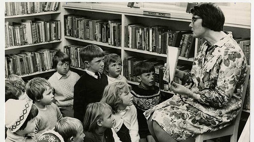 A woman captivates children with a compelling narrative at the library.