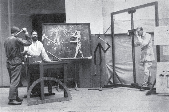 Three men standing in science lab and one man taking photo of experiments. 